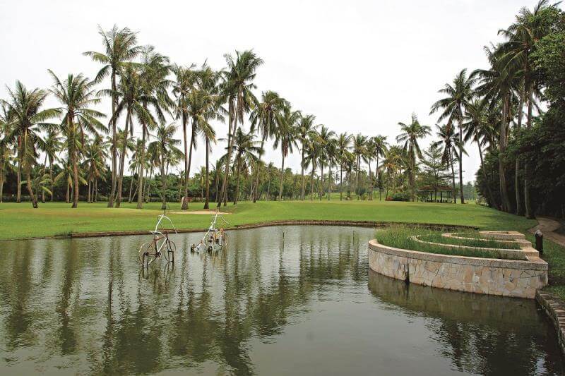 golf-kaohsiung-pt10 a line of tall palm trees in the background under a bright sky