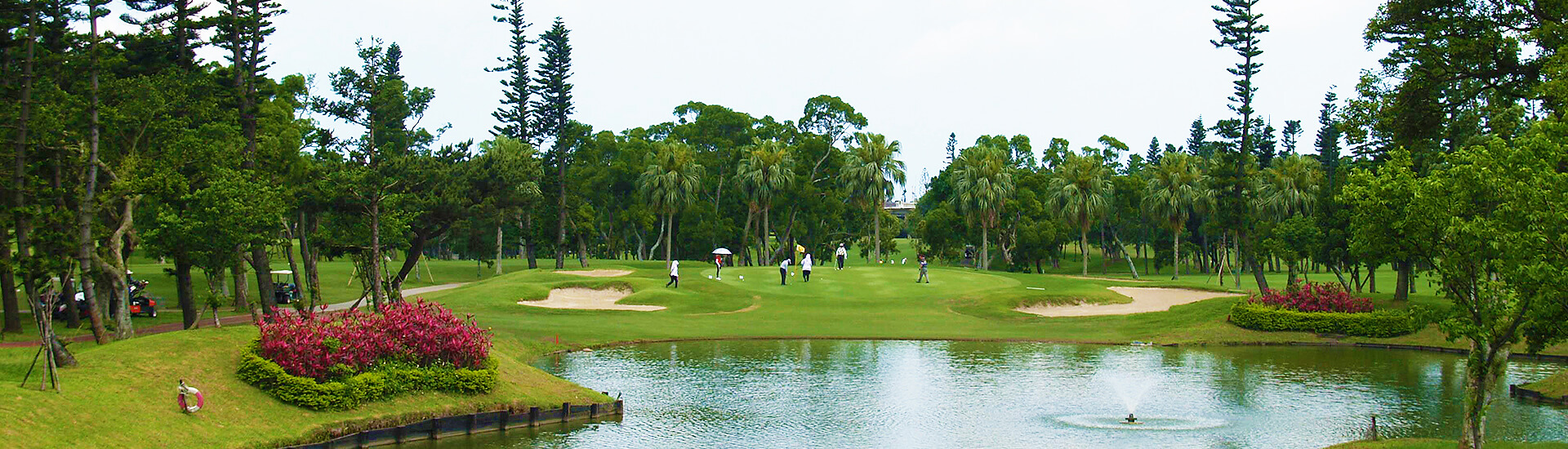 panoramic view of a lush green golf course featuring a water hazard pond
