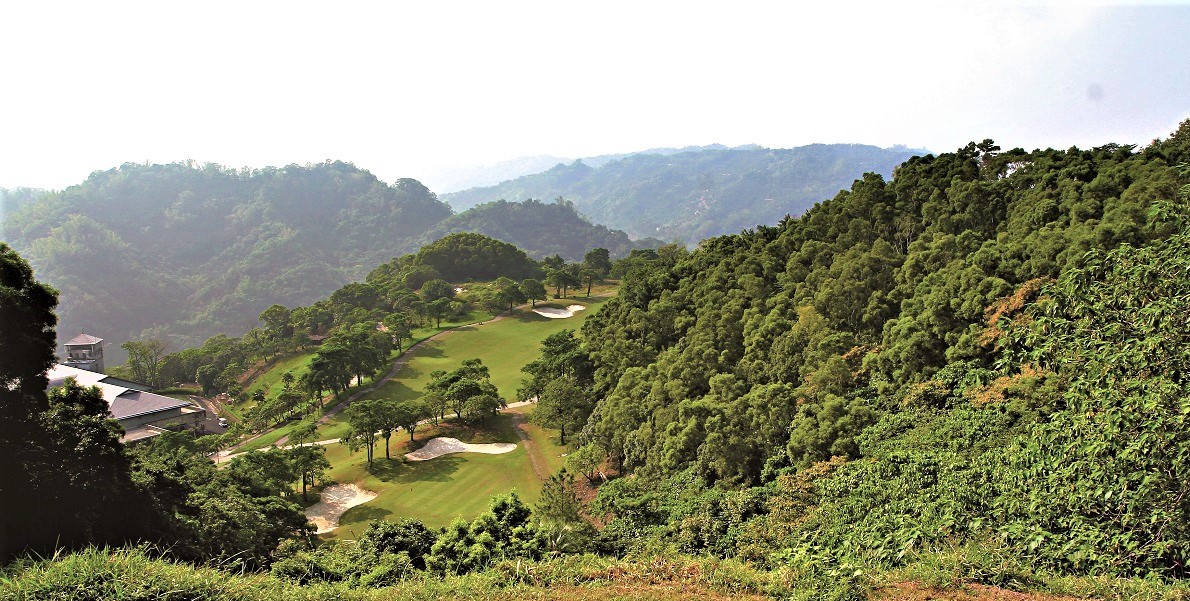 green mountainous terrain, with overlapping ridges under a bright sky